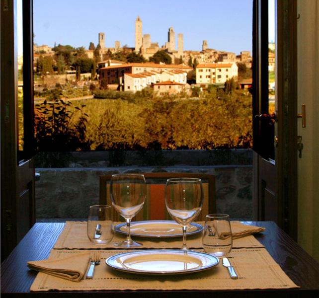 een tafel met een bord en twee wijnglazen bij Locanda Viani in San Gimignano