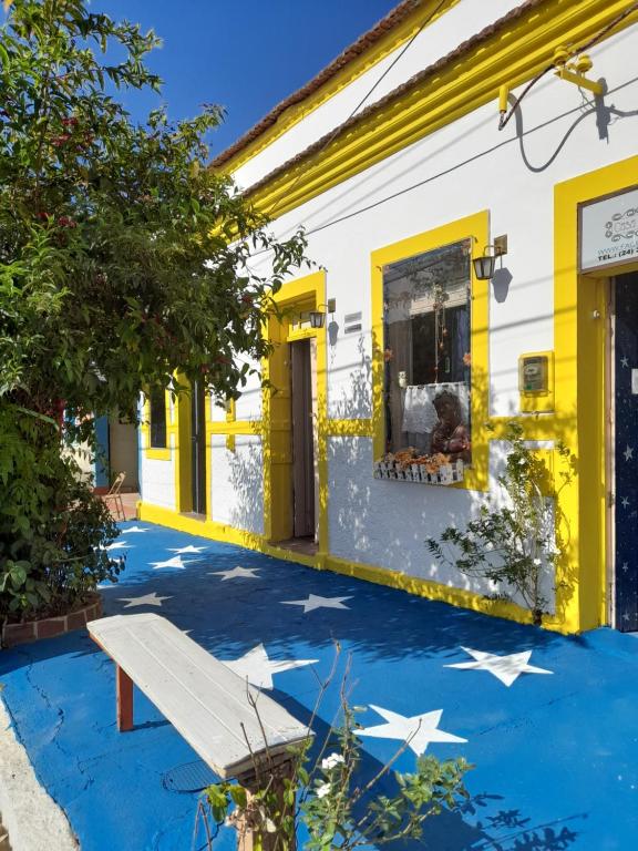 a house with yellow and white walls and stars painted on the floor at Pousada no Centro de Conservatória Sandrinho ChicChic in Conservatória
