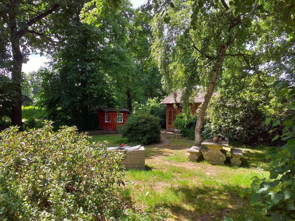 een tuin met een rode hut op de achtergrond bij De Geheime Tuin - Huisje in 't Groen in Epe