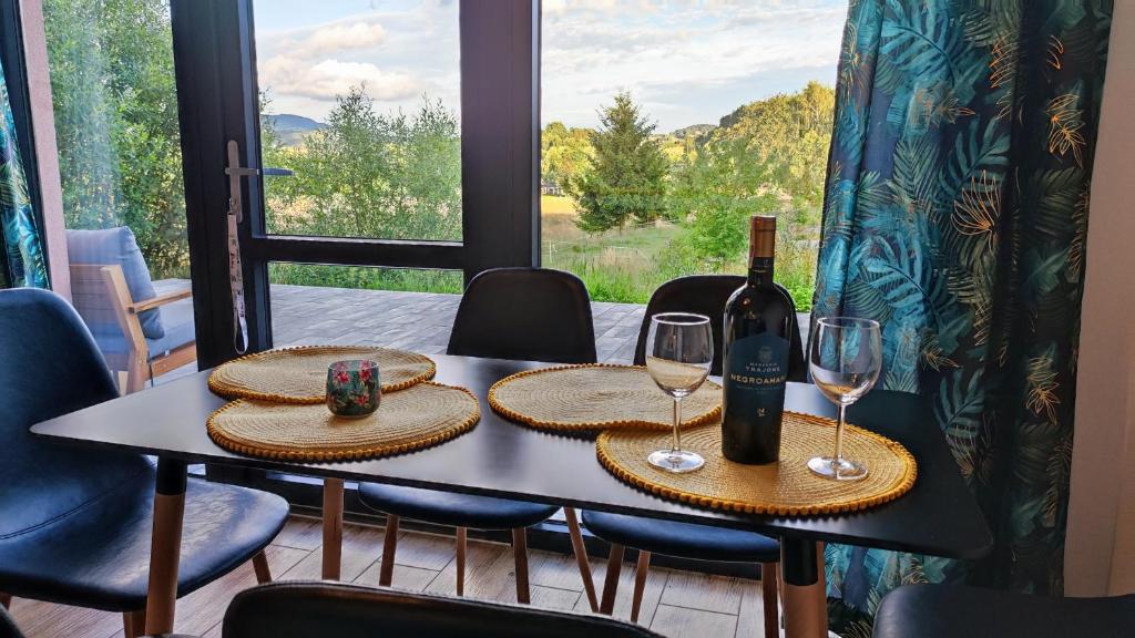 a table with a bottle of wine and two glasses at Blu Raj - domy w Sudetach in Głuszyca