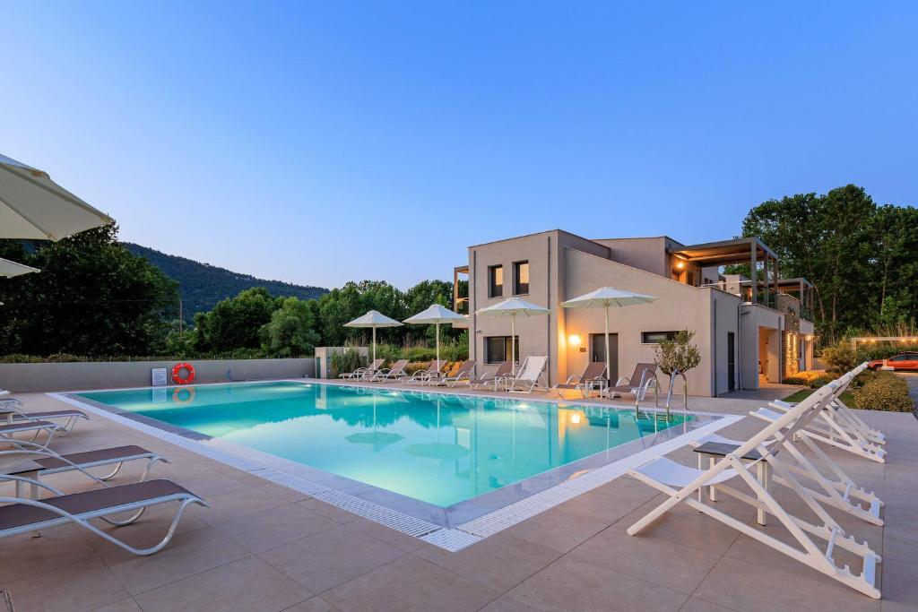 a swimming pool with chairs and a house at Marajo Suites in Skala Potamias