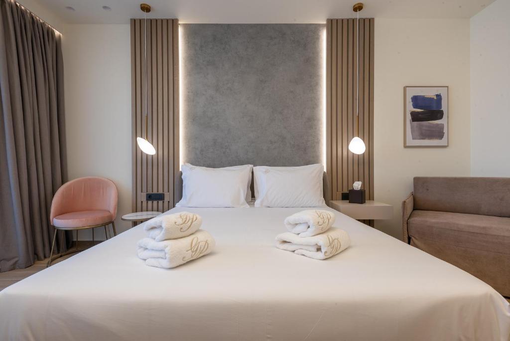 a bedroom with a white bed with towels on it at GRAND PATELLI in Myrina