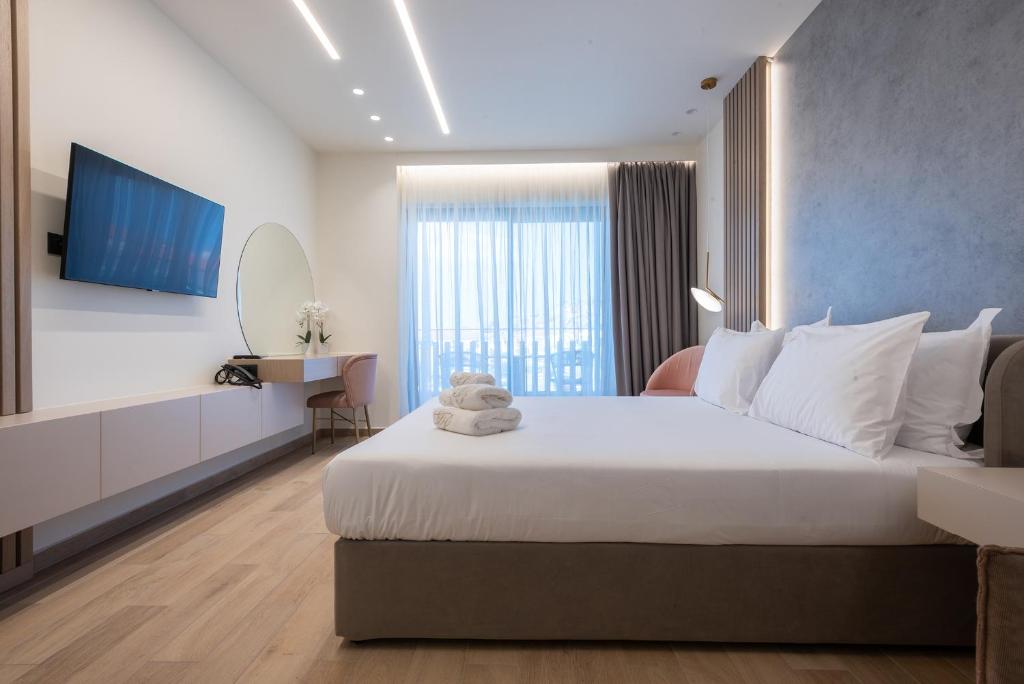 a bedroom with a large white bed and a television at GRAND PATELLI in Myrina