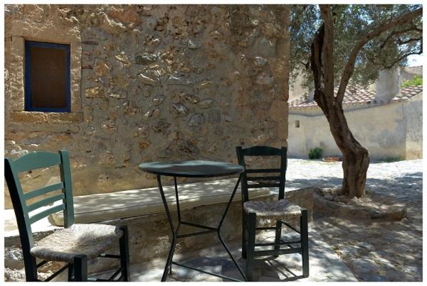 two chairs and a table and two chairs and a tree at NEFELI castle stone house inside the fortress in Monemvasia