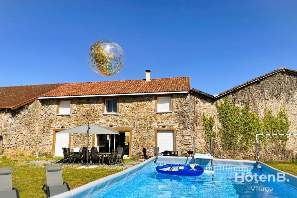 ein Ballon fliegt über einen Pool vor einem Haus in der Unterkunft La Vedrenne Grange connectée à Limoges in Bonnac-la-Côte