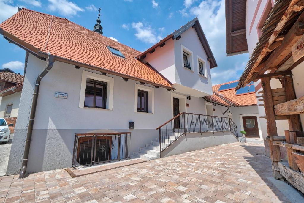 una casa blanca con techo naranja en AUžlak hiša, apartments. en Luče