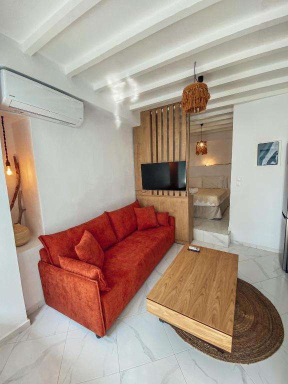 Una sala de estar con un sofá rojo y una mesa. en Evagelias suite, en Skopelos Town