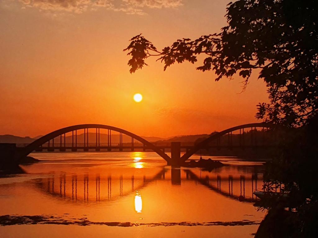 uma ponte sobre um rio ao pôr-do-sol em Watersedge Seaviews em Kenmare