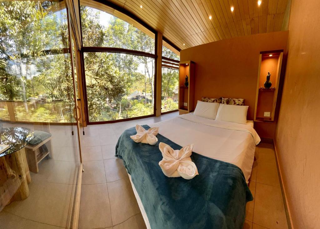 a bedroom with a bed and a large window at Saguamby Mindo Lodge in Mindo