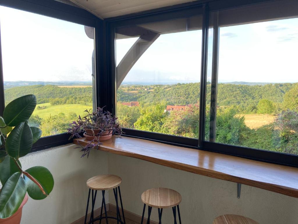 two stools in front of a window with a view at Gîte "le haut des Poujades" in Reilhaguet