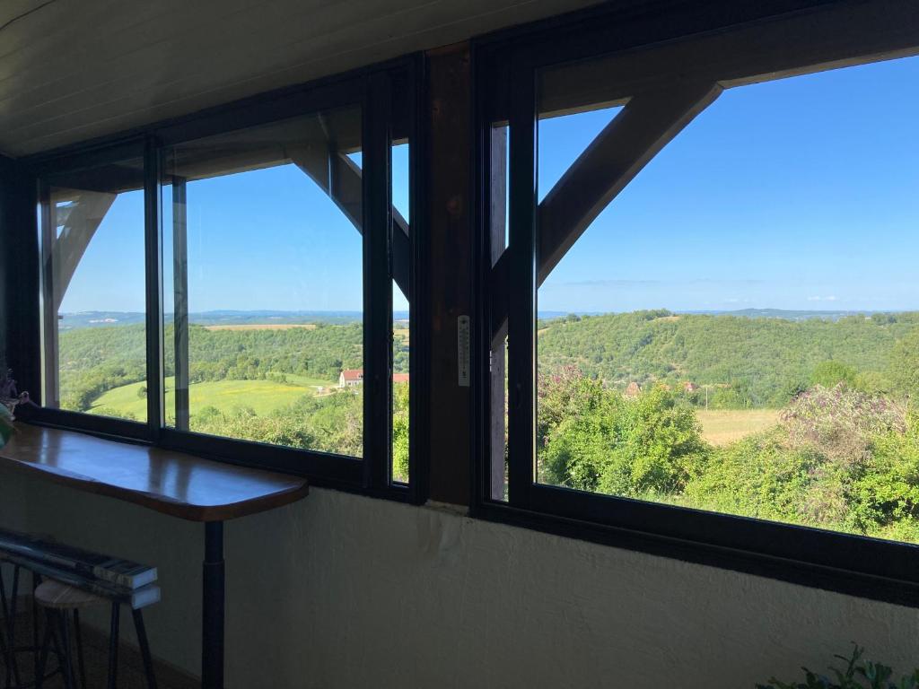 a room with windows looking out at the countryside at Gîte "le haut des Poujades" in Reilhaguet