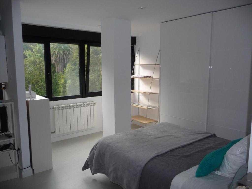 a white bedroom with a bed and a window at Los Infantes 954 in Santander