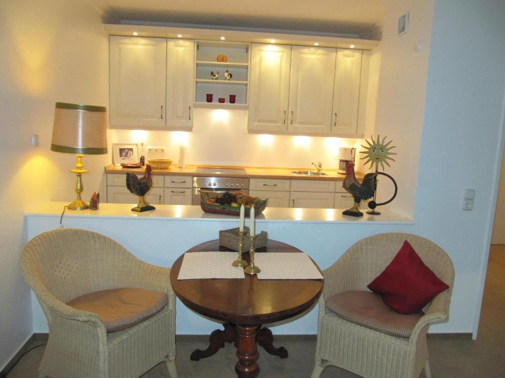 une cuisine avec une table, deux chaises et un comptoir dans l'établissement Appartement Deckerstraße 19-21 Appartement 10, à Westerland