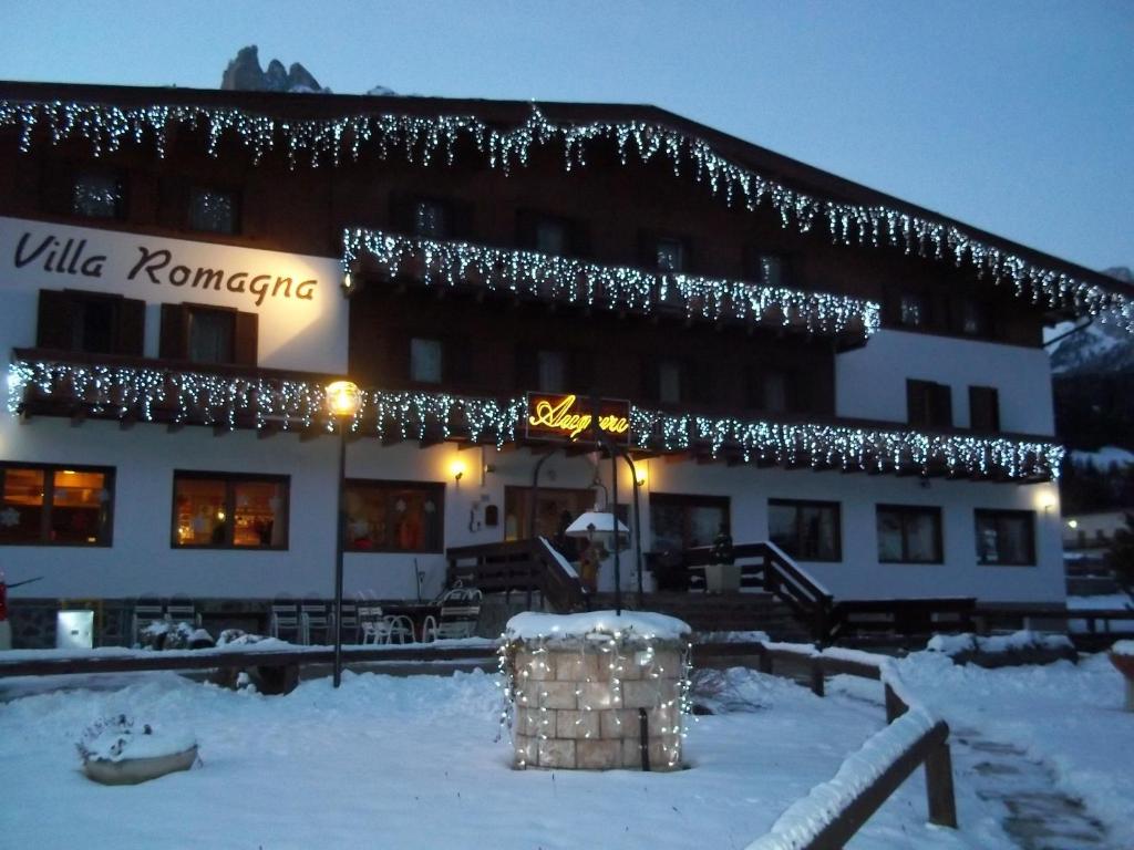 un bâtiment recouvert de lumières de Noël dans la neige dans l'établissement Casa per Ferie Villa Romagna, à Pozza di Fassa