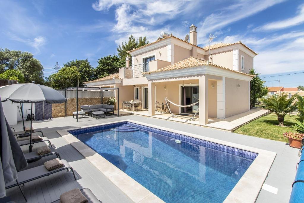 a villa with a swimming pool in front of a house at Villa Maya in Almancil