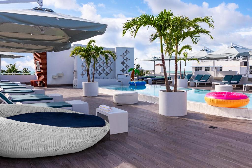 a hotel patio with chairs and a pool with palm trees at Dream South Beach, by Hyatt in Miami Beach