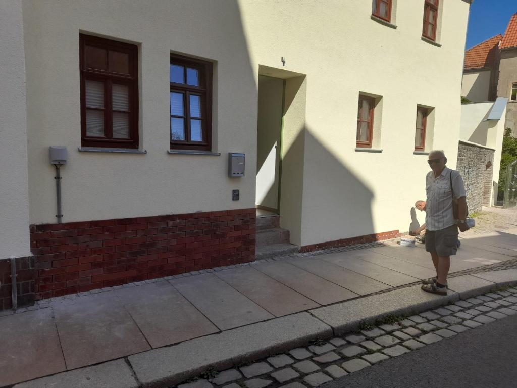 Un uomo che cavalca uno skateboard lungo un marciapiede di fronte a una casa di Kunstgasse 4+5 ad Altenburg