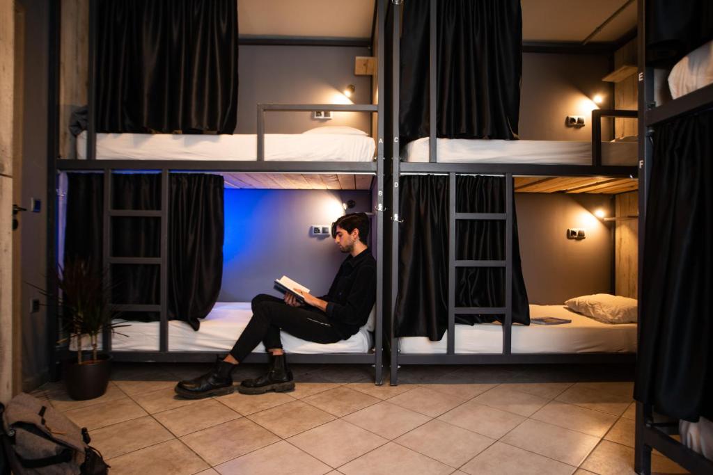 a man sitting on a bed in a room with bunk beds at Bedway Athens Hostel in Athens