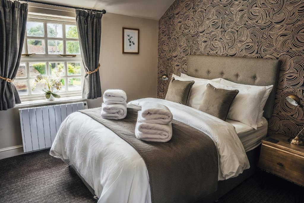 een slaapkamer met een bed met handdoeken erop bij The Bull Inn in Woolpit