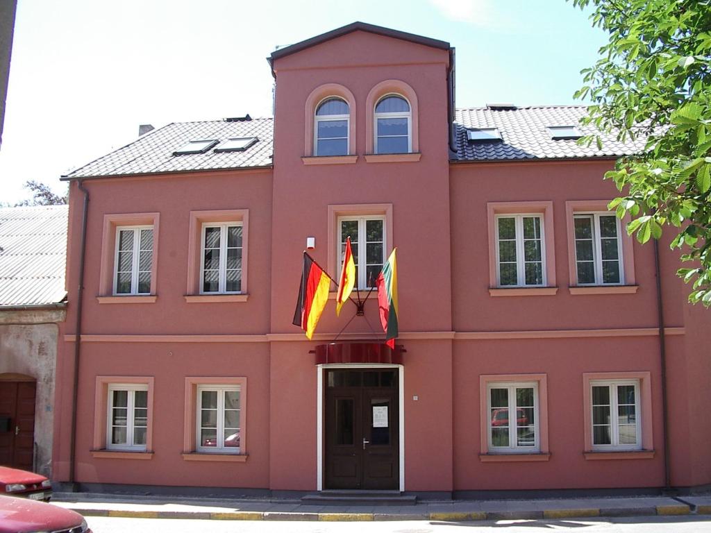 un edificio rojo con banderas delante en Simon-Dach-Haus en Klaipėda