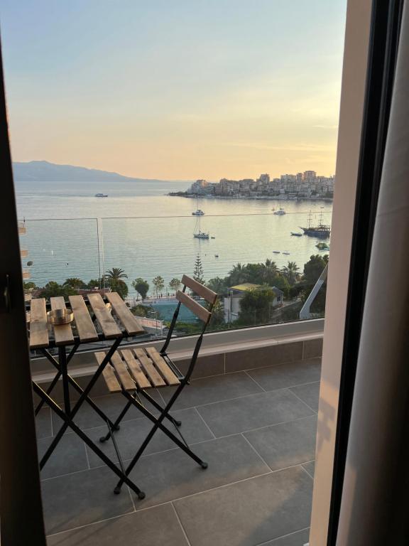 una mesa y una silla en un balcón con vistas al agua en Hotel Kanes en Sarandë