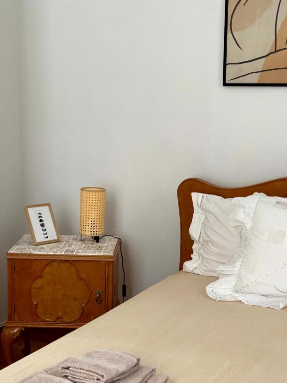 a bedroom with a bed and a night stand with a lamp at Η Ελπίδα και η Γιάννα ξεκίνησαν ένα χώρο cute in Volos
