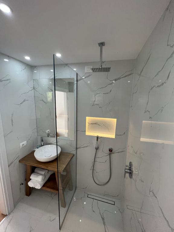 a bathroom with a sink and a glass shower at Kanes Bohemian Boutique Hotel in Sarandë