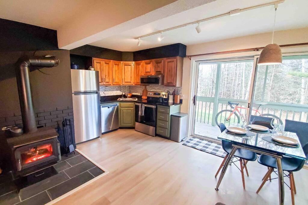 a kitchen with a stove and a table with a fireplace at Burke Abode - Trailside Condo with King & Full Beds in East Burke