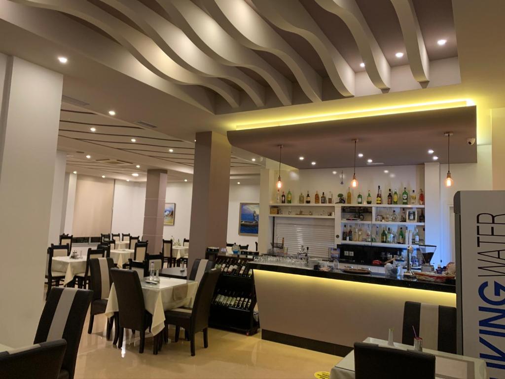 un restaurant avec des tables et des chaises blanches et un bar dans l'établissement MARIKSEL Hotel, à Ksamil
