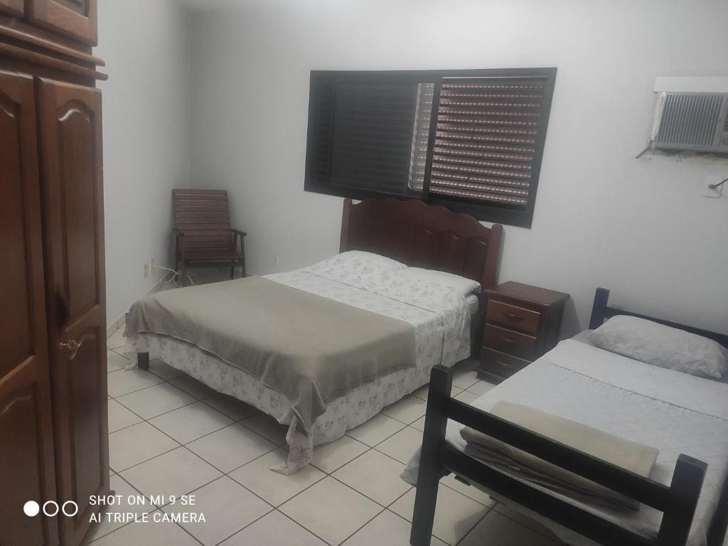 a bedroom with two beds and a flat screen tv at AP 04 DO CANTINHO DO SOSSEGO in Dourados