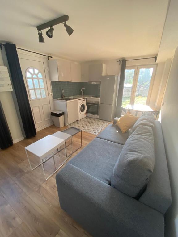 a living room with a blue couch and a kitchen at Une pause en Ile de France - 450 M RER E in Villiers-sur-Marne