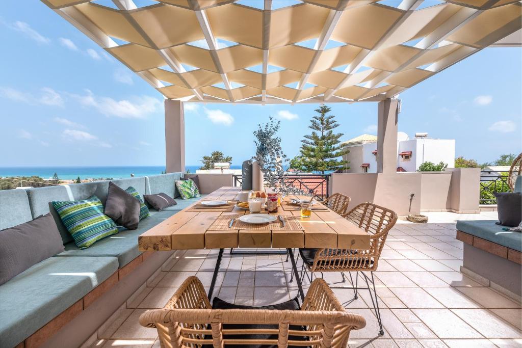 a patio with a wooden table and chairs and the ocean at Villa VerdeBlu Rethymno Crete in Rethymno Town