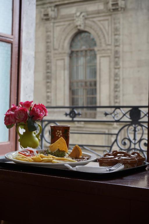a table with two plates of food and a vase of roses at Hotel Isabel in Mexico City