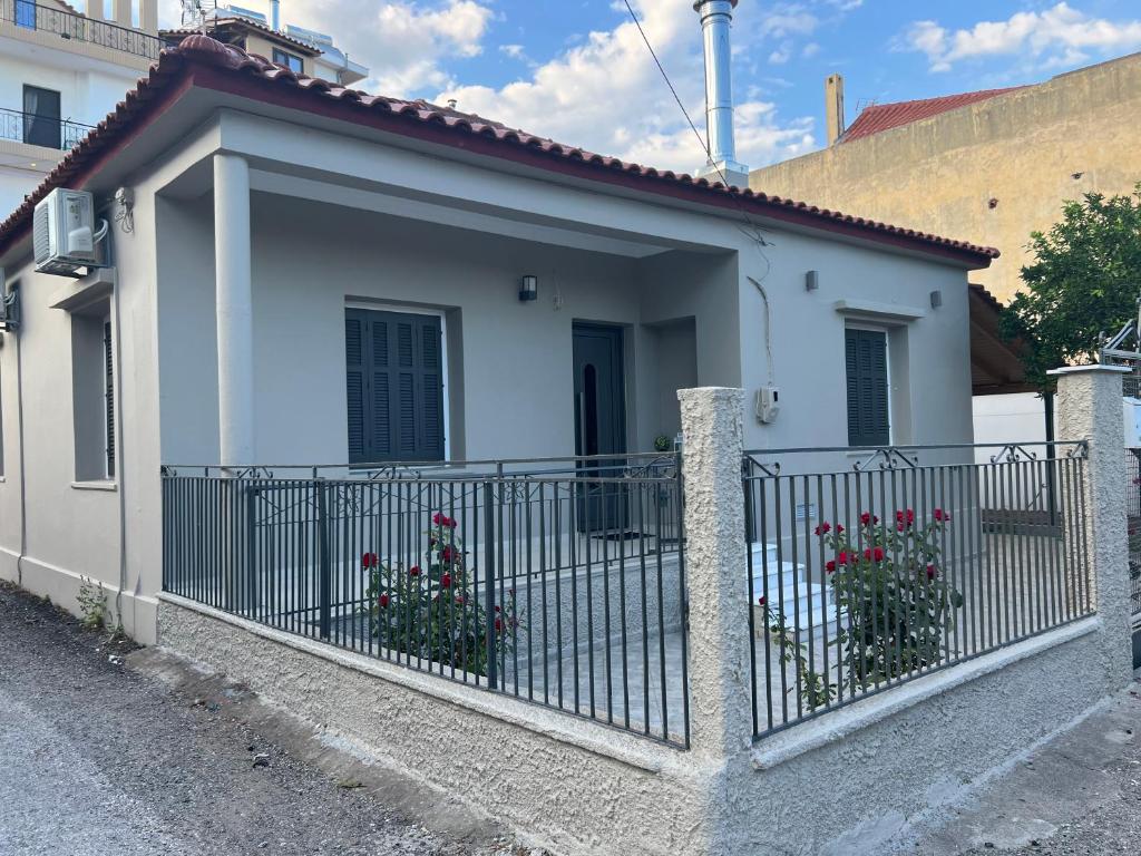 uma casa branca com uma cerca e flores em Όμορφη μονοκατοικία με 2 υπνοδωμάτια και τζάκι em Lepanto
