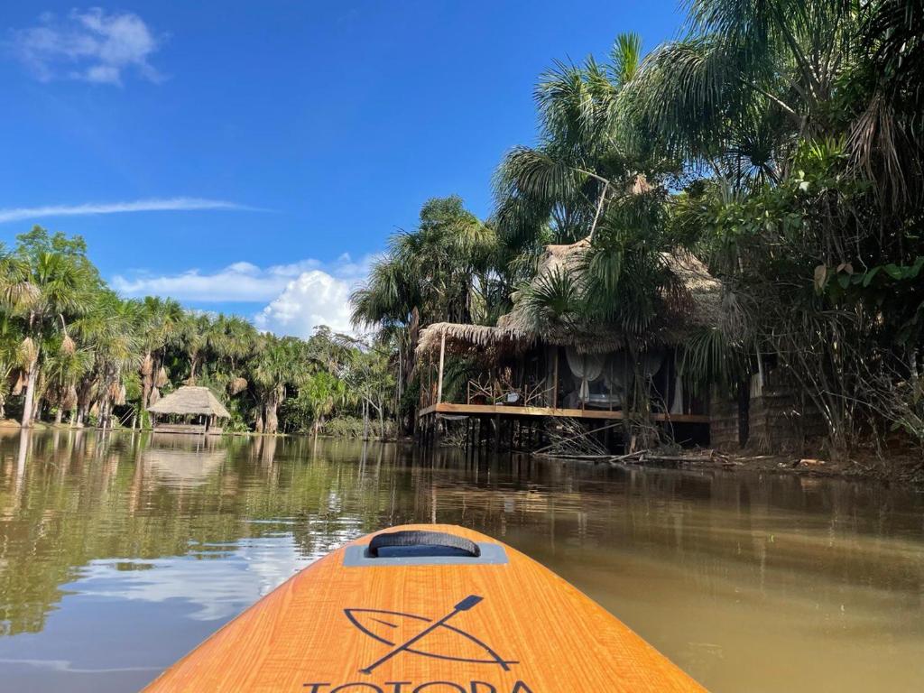 un kayak naranja en el agua con casa atroz en Camu camu jungle villa on Aguajale lake - supboard&vinyl en Iquitos