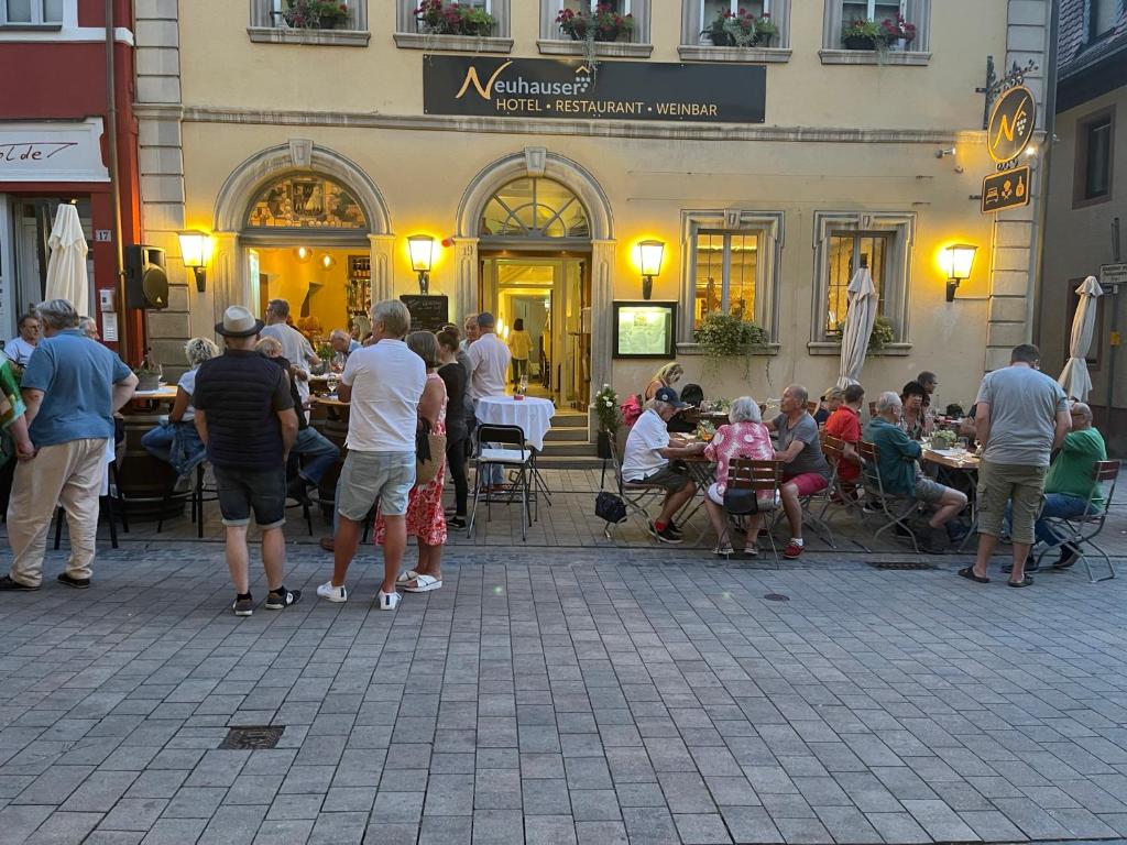 um grupo de pessoas sentadas em mesas fora de um edifício em Hotel Neuhauser em Volkach