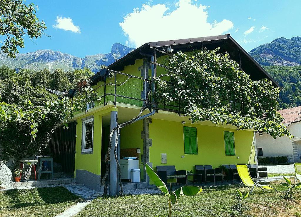 une maison jaune avec une table et des chaises devant elle dans l'établissement Hiša Planica, à Kobarid