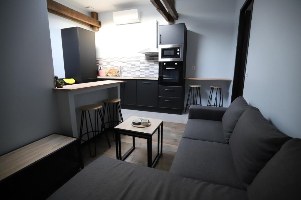 a living room with a couch and a kitchen at Appartement neuf climatisé in Aramits