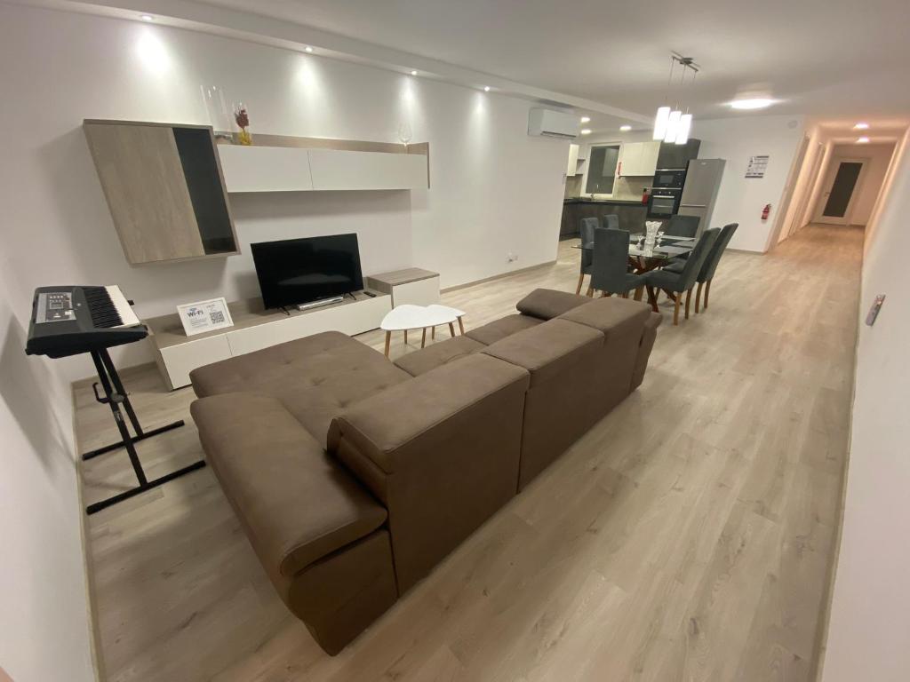 ein Wohnzimmer mit einem braunen Sofa und einem Tisch in der Unterkunft Modern Apartment with Large Outdoor Area - Sleeps 7, Close to Malta International Airport in Luqa