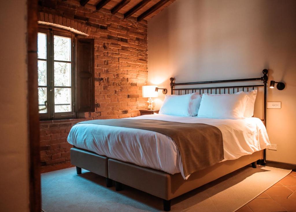 a bedroom with a bed and a brick wall at Borgo San Vincenzo in Montepulciano