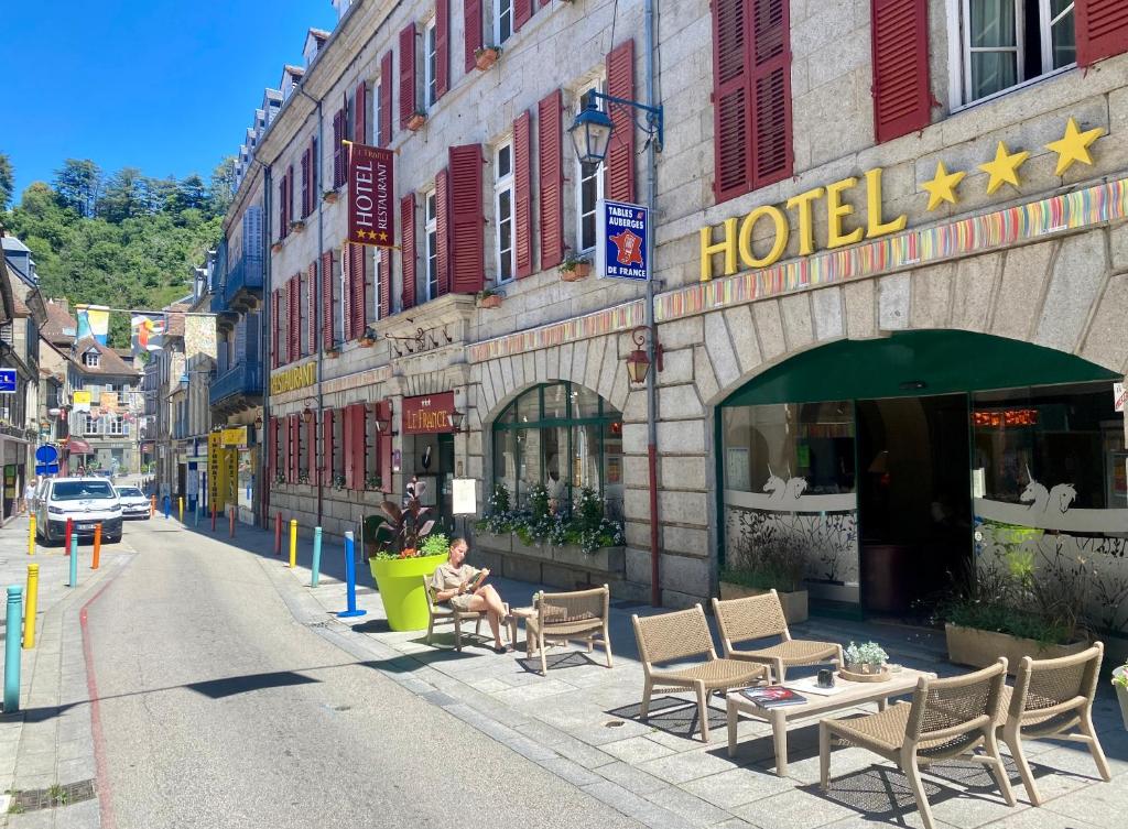 a person sitting on a bench in front of a hotel at Hôtel Le France in Aubusson