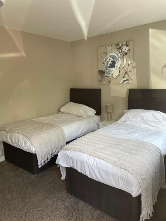 2 bedden in een kamer met witte lakens bij Tall Pines Lodges in Lulsgate Bottom