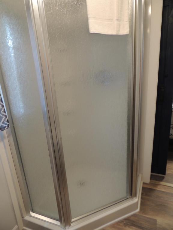 a shower with a glass door in a bathroom at White Caps Motel in Port Clinton