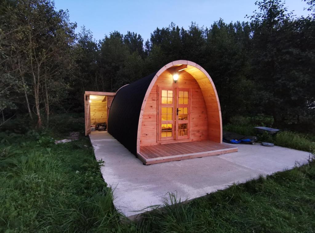 a small wooden cabin with a door in the grass at Charmant POD en bois près d'un plan d'eau in Nielles-lès-Ardres