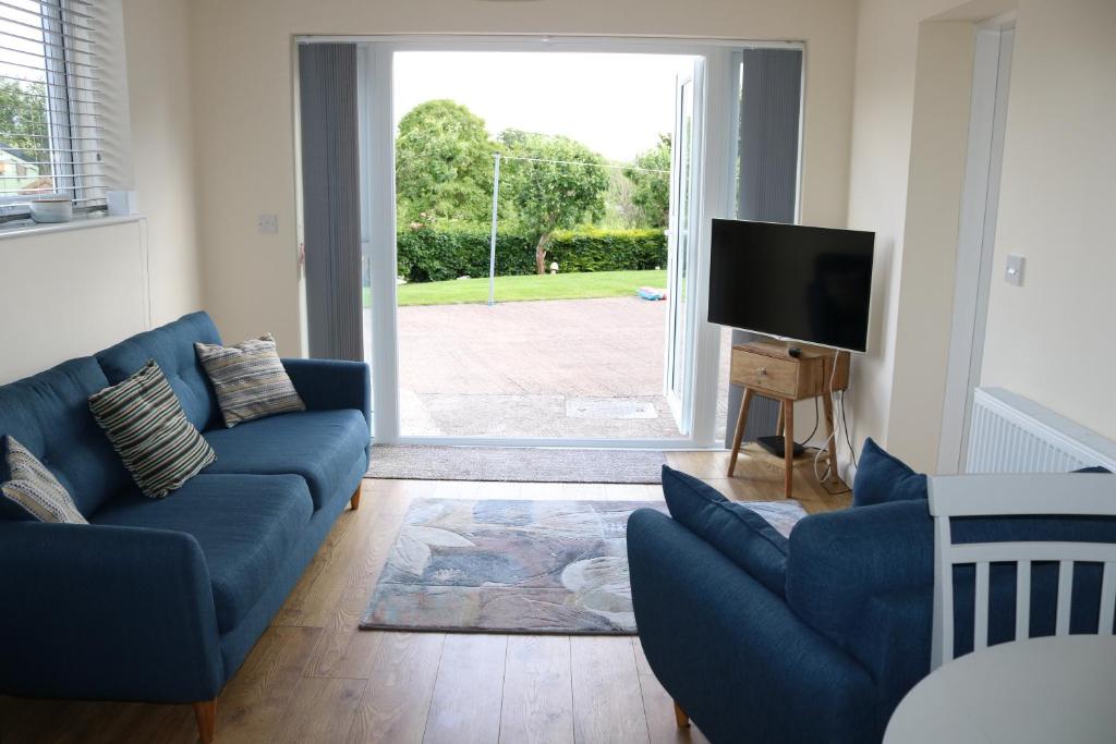 a living room with a blue couch and a tv at Lovely 1 bedroom basement apartment with stunning views in Bodfari