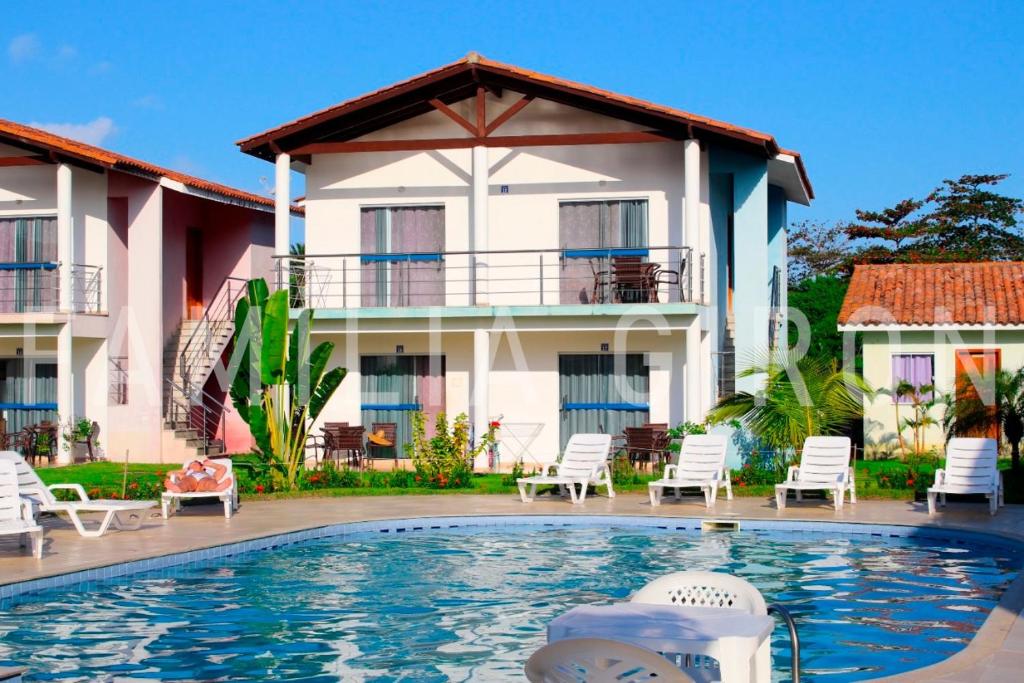 a villa with a swimming pool in front of a building at Flats a 100 mts da Praia in Porto Seguro