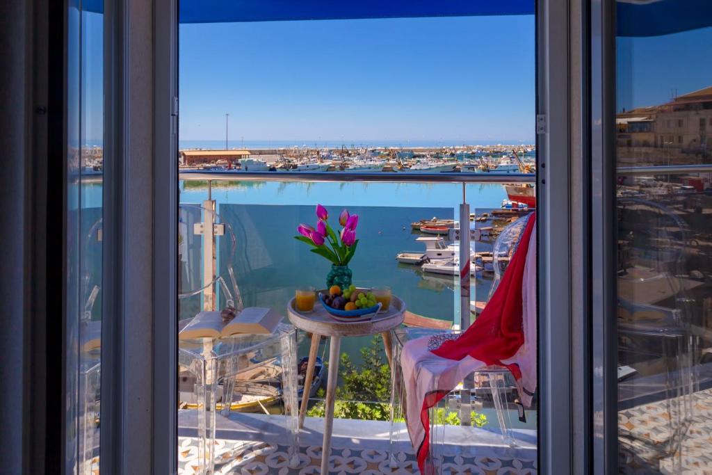 a balcony with a table and a view of a harbor at Vittoria Luxury Rooms in Sciacca