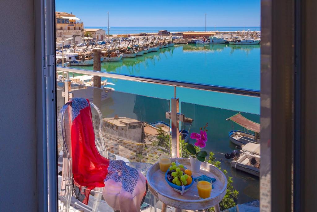 a view of a harbor from a balcony with a table with fruit at Vittoria Luxury Rooms in Sciacca