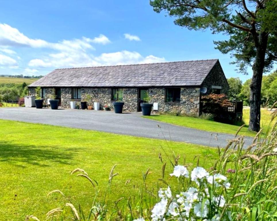 a stone building with a grassy field in front of it at Lune Cottage nestled between Lake District and Yorkshire Dales in Tebay