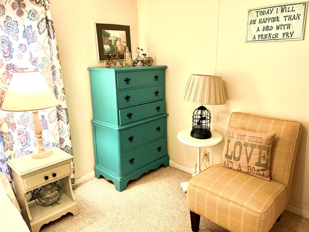 a bedroom with a blue dresser and a chair at White Caps Motel in Port Clinton